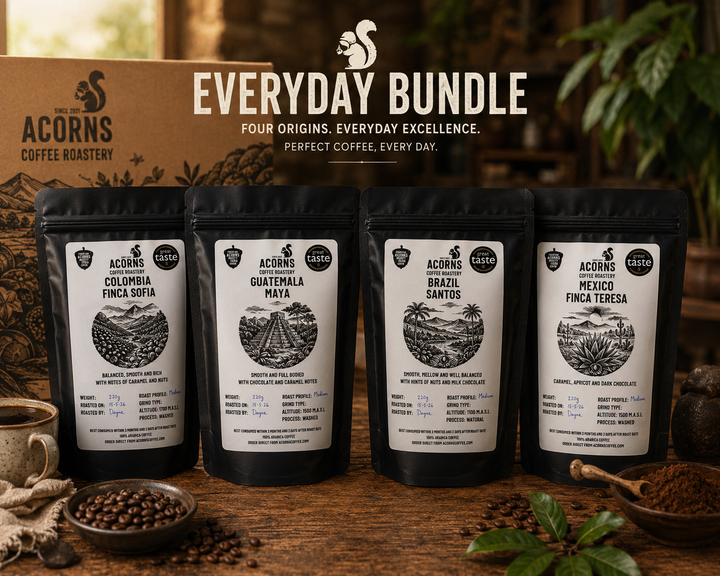 Four Acorns Coffee Roastery coffee bags with labels on a wooden surface, featuring the brand logo and &