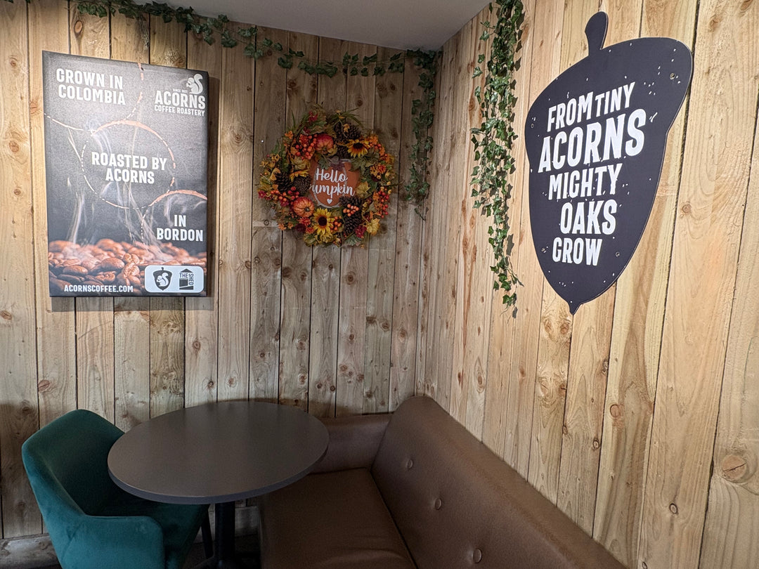 Wooden wall with Acorns Coffee posters, a wreath, and a sign.