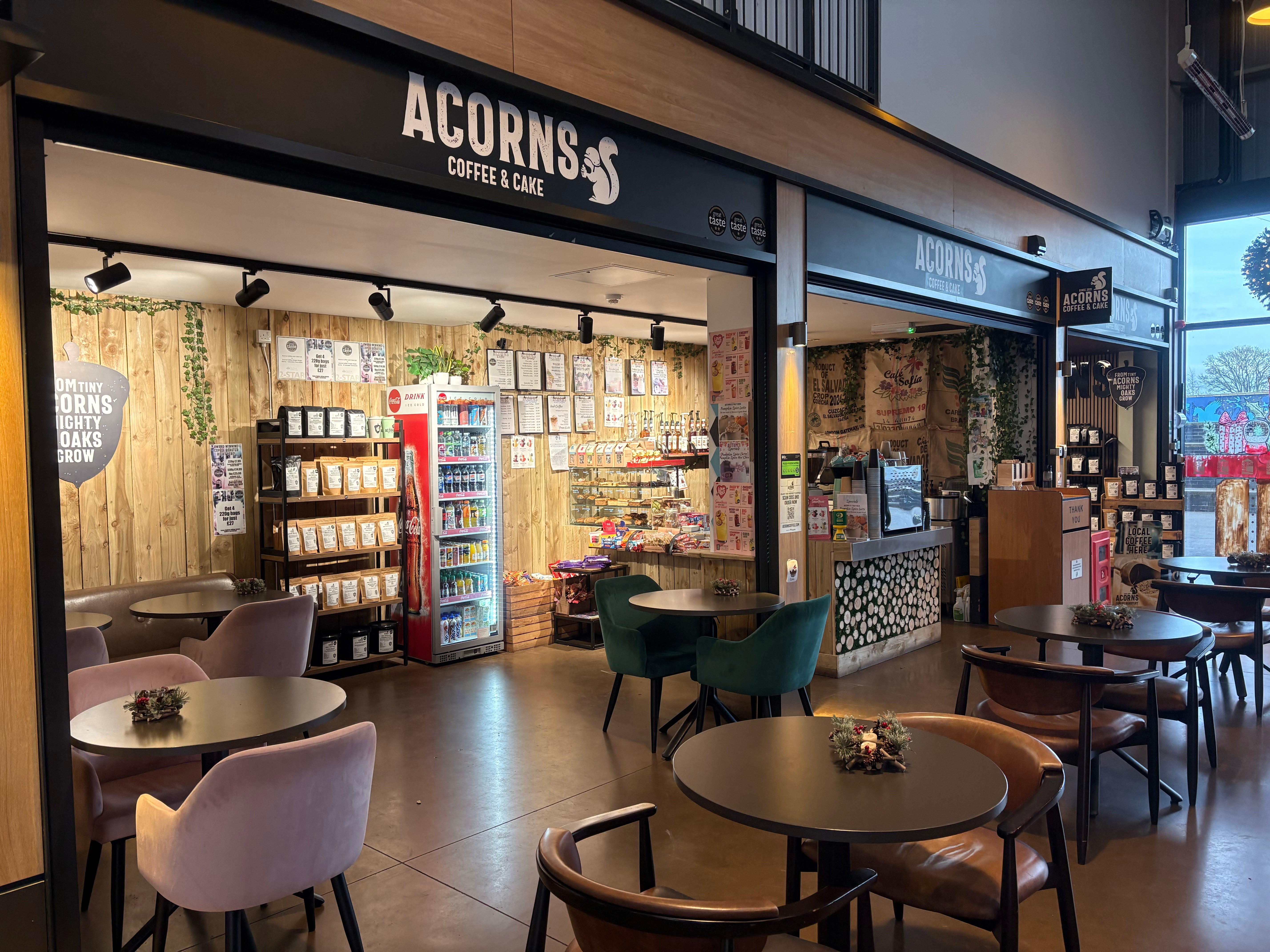 Acorns Coffee & Cake store interior with tables, chairs, and a coffee machine.