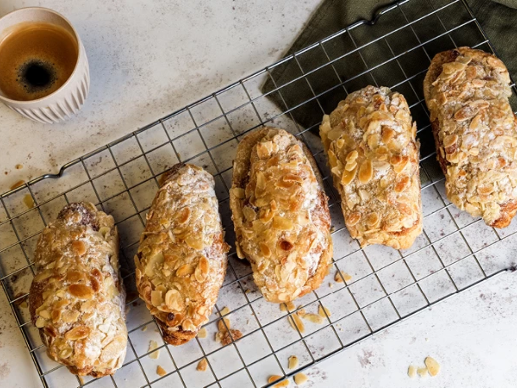 Pastry items on a cooling rack with a cup of coffee in the background