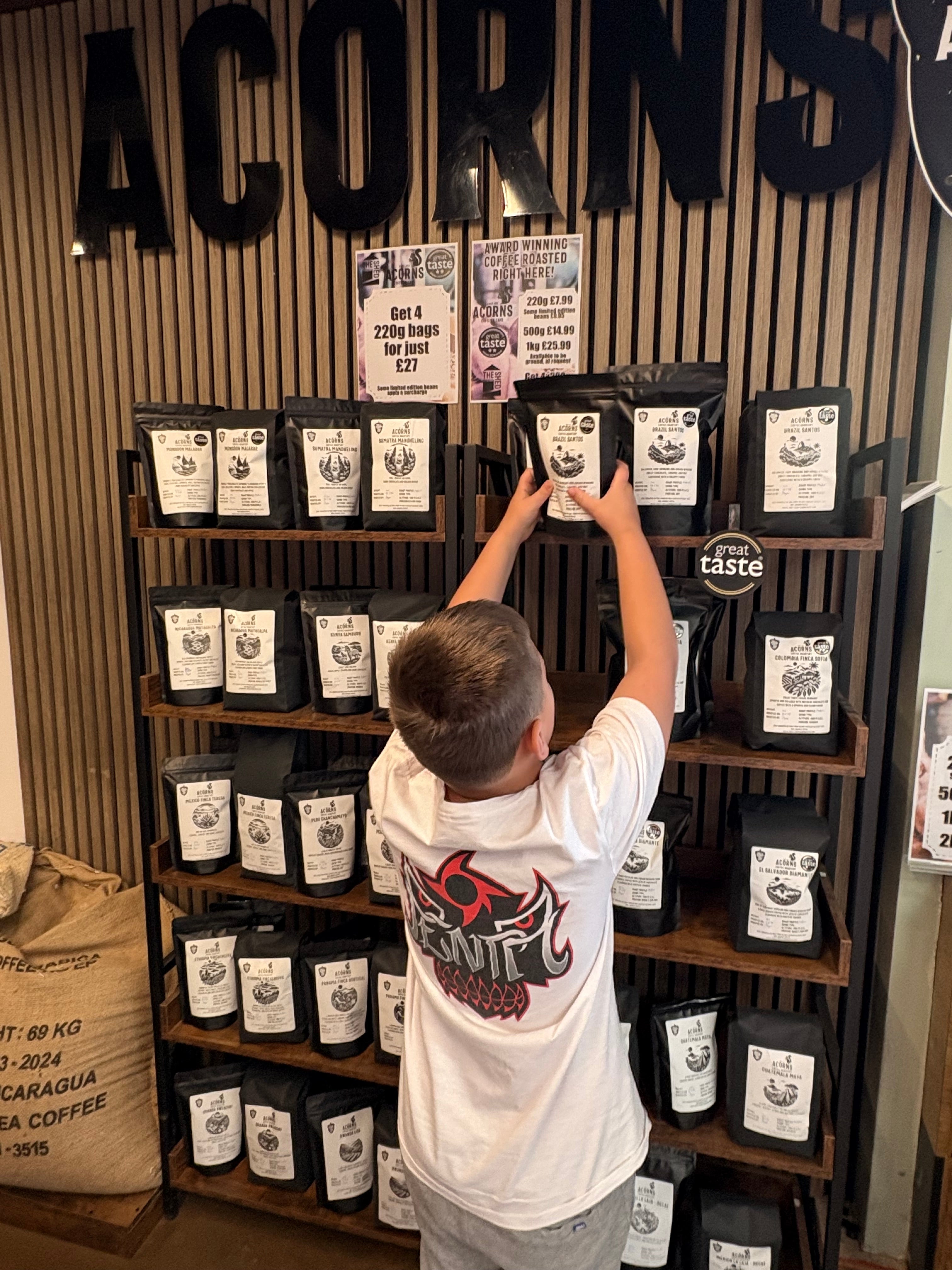 George, aged 7, organizing coffee bags on a shelf in a store.